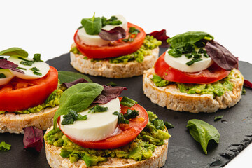 Ricecakes with mozzarella avocado spinach onion on a stone on a white background