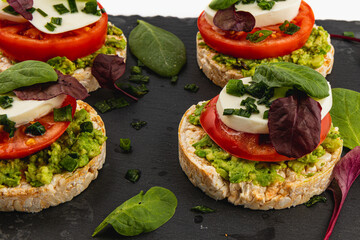 Ricecakes with mozzarella avocado spinach onion on a stone on a white background