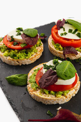 Ricecakes with mozzarella avocado spinach onion on a stone on a white background