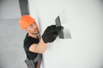 Tradesman on stilts plastering drywall in home