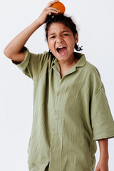 Young boy showcasing a vibrant orange fruit while making eye contact with the camera in a stylish pose