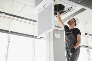 Worker repairing ceiling air conditioning unit