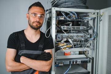 A technician works with server equipment in a data center. A man commutes wires in a server room