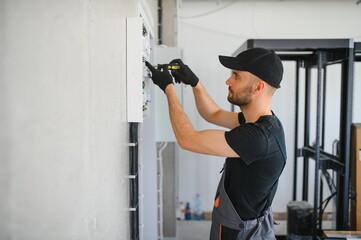 Male electrician working in a switchboard with fuses