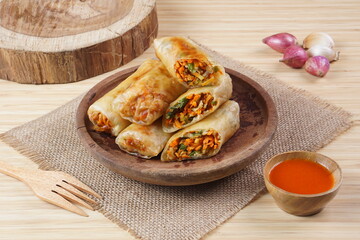 Lumpia or Lunpia, is a traditional snack from central java Indonesia consists of bamboo shoots eggs and meat or shrimp, photographed with wood theme props, studio lighting