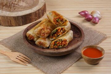 Lumpia or Lunpia, is a traditional snack from central java Indonesia consists of bamboo shoots eggs and meat or shrimp, photographed with wood theme props, studio lighting