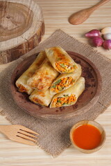Lumpia or Lunpia, is a traditional snack from central java Indonesia consists of bamboo shoots eggs and meat or shrimp, photographed with wood theme props, studio lighting