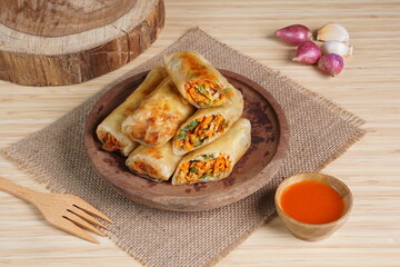 Lumpia or Lunpia, is a traditional snack from central java Indonesia consists of bamboo shoots eggs and meat or shrimp, photographed with wood theme props, studio lighting