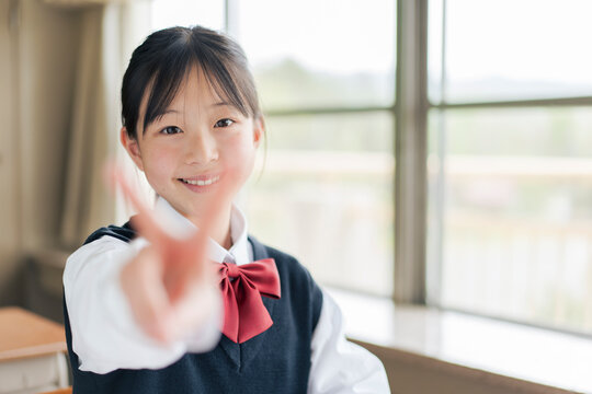 ピースサインをする笑顔の女子中学生