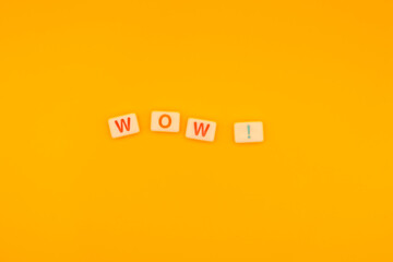 Scrabble tiles spelling WOW on vibrant yellow background