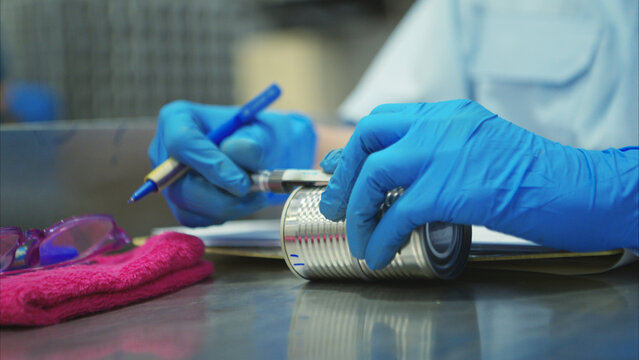 Production control supervisor inspects the can in the production line of a canned fish factory