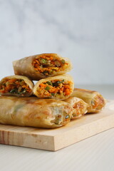 Lumpia or Lunpia, is a traditional snack from central java Indonesia consists of bamboo shoots eggs and meat or shrimp, photographed with wood theme props, studio lighting