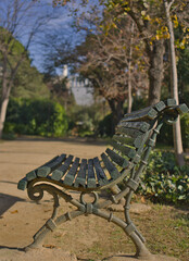 A classic park bench with a backdrop of trees and greenery. The framing highlights the blend of rustic architecture with the serenity of nature, evoking nostalgia and relaxation. 