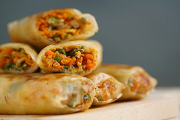 Lumpia or Lunpia, is a traditional snack from central java Indonesia consists of bamboo shoots eggs and meat or shrimp, photographed with wood theme props, studio lighting