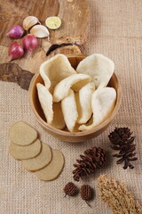 Traditional Indonesian kerupuk snacks, made from catfish, served in a wooden place on a white table with a studio lighting