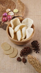Traditional Indonesian kerupuk snacks, made from catfish, served in a wooden place on a white table with a studio lighting
