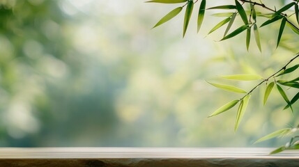 Obraz premium Wooden table with bamboo leaves and blurred green background.