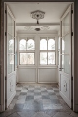 view of an entrance with tall open doors and arched windows with patterned grey and white floor