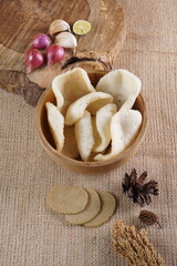Traditional Indonesian kerupuk snacks, made from catfish, served in a wooden place on a white table with a studio lighting