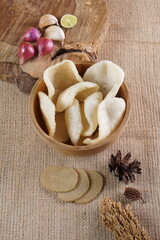 Traditional Indonesian kerupuk snacks, made from catfish, served in a wooden place on a white table with a studio lighting