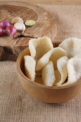 Traditional Indonesian kerupuk snacks, made from catfish, served in a wooden place on a white table with a studio lighting