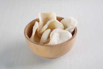 Traditional Indonesian kerupuk snacks, made from catfish, served in a wooden place on a white table with a studio lighting
