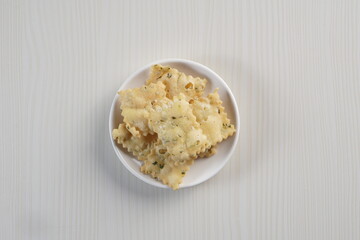 wonton chips on a small white plate on a white table with studio lighting