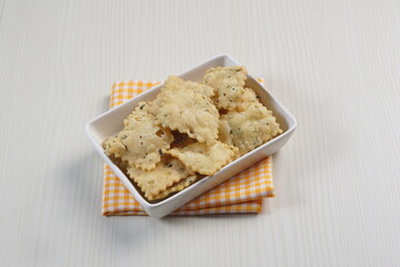 wonton chips on a small white plate on a white table with studio lighting