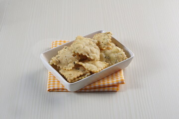 wonton chips on a small white plate on a white table with studio lighting