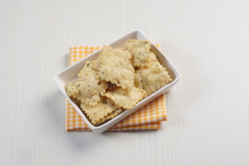 wonton chips on a small white plate on a white table with studio lighting