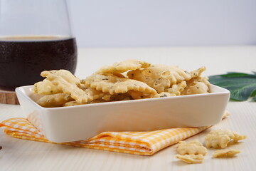 wonton chips in a small white ceramic container on a white table, served with black coffee, with studio lighting