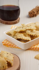 wonton chips in a small white ceramic container on a white table, served with black coffee, with studio lighting