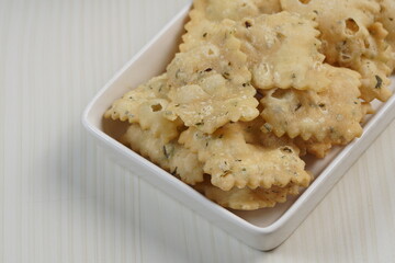 wonton chips on a small white plate on a white table with studio lighting