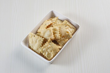 wonton chips on a small white plate on a white table with studio lighting