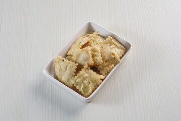 wonton chips on a small white plate on a white table with studio lighting