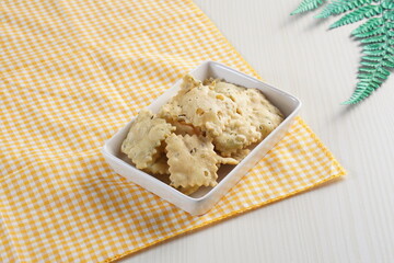 wonton chips on a small white plate on a white table with studio lighting