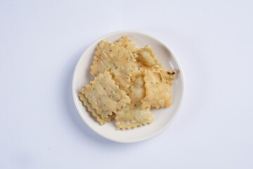wonton chips on a small white plate on a white table with studio lighting