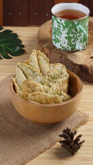 Crispy and savory spinach chips. Made from spinach leaves and rice flour, in a wooden bowl, with wood properties, and studio lighting