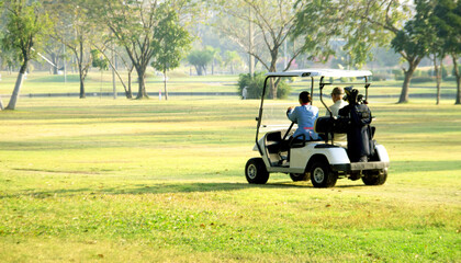 A golf cart transporting golfers on a lush green golf course. Focus on the cart and golfers,...