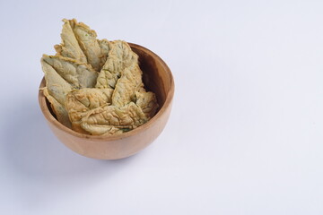 Crispy and savory spinach chips. Made from spinach leaves and rice flour, in a wooden bowl, with a white background and studio lighting