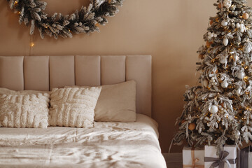 A bedroom with a white bed and a Christmas tree in the corner. The bed is covered with a white blanket and pillows