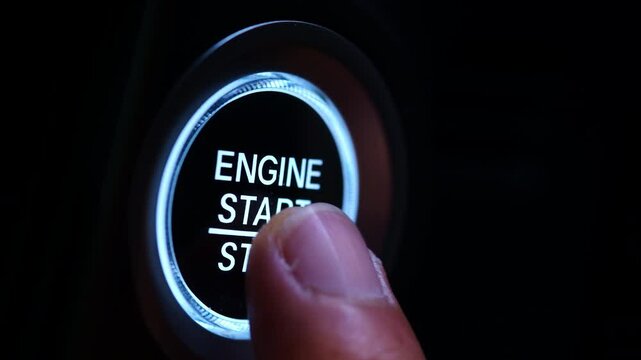 The driver's hand is pressing the car start button. Concept of transportation and technology	