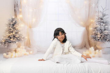 5 year old Latina brunette girl with eyeglasses among decorated trees is excited to celebrate Christmas and New Year