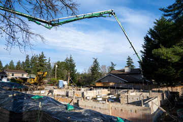 Concrete Boom Pump Truck with Z-Fold boom arm pumping cement for a residential house foundation, sunny winter day construction project  © knelson20
