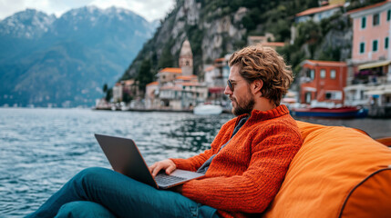 Fototapeta premium Remote Worker Relaxing on a Boat with Laptop Against Scenic Lake and Mountain View