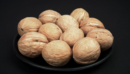 A full plate of dry walnut in black background