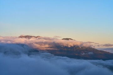 Morning clouds envelop a majestic volcano at dawn, revealing nature's silent beauty