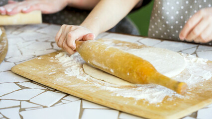 Small hands shaping dough on a floured board