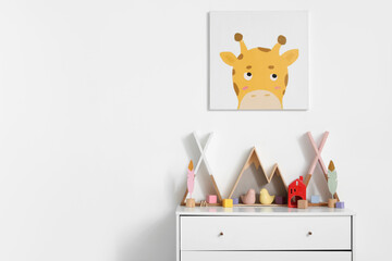 Stylish interior of children's room with chest of drawers, picture and toys