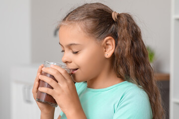 Cute girl drinking sweet hot cocoa in kitchen
